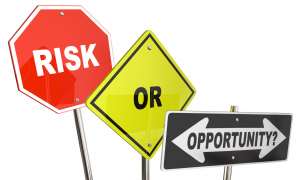 Three road signs: a red octagon labeled "RISK," a yellow diamond with "OR," and a black sign pointing left and right …